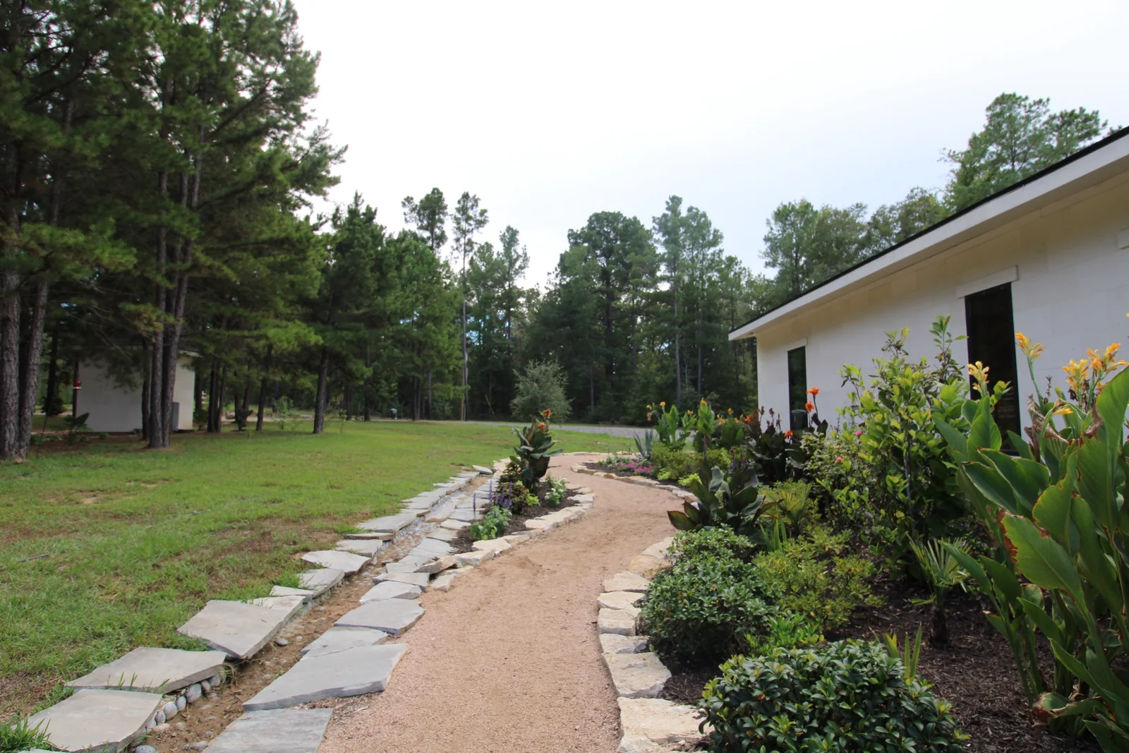 Stone-edged gravel path beside flowering plants along the side of the home