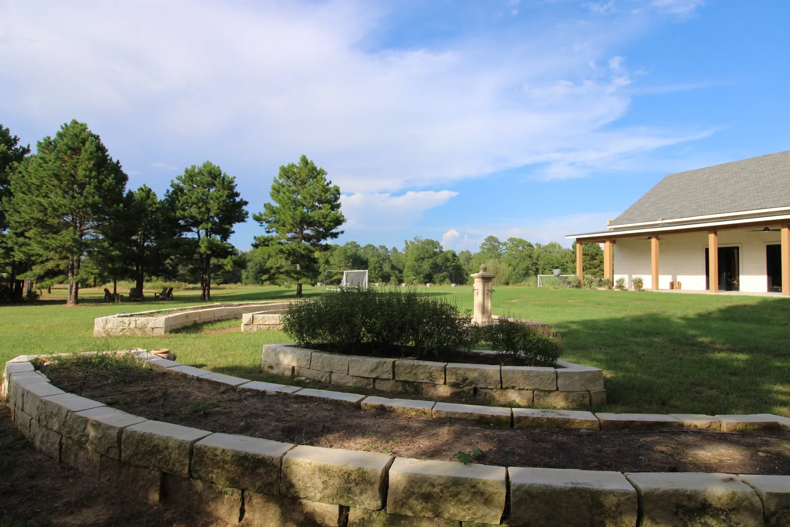 Curving stone garden beds and fountain detail with the long covered porch beyond